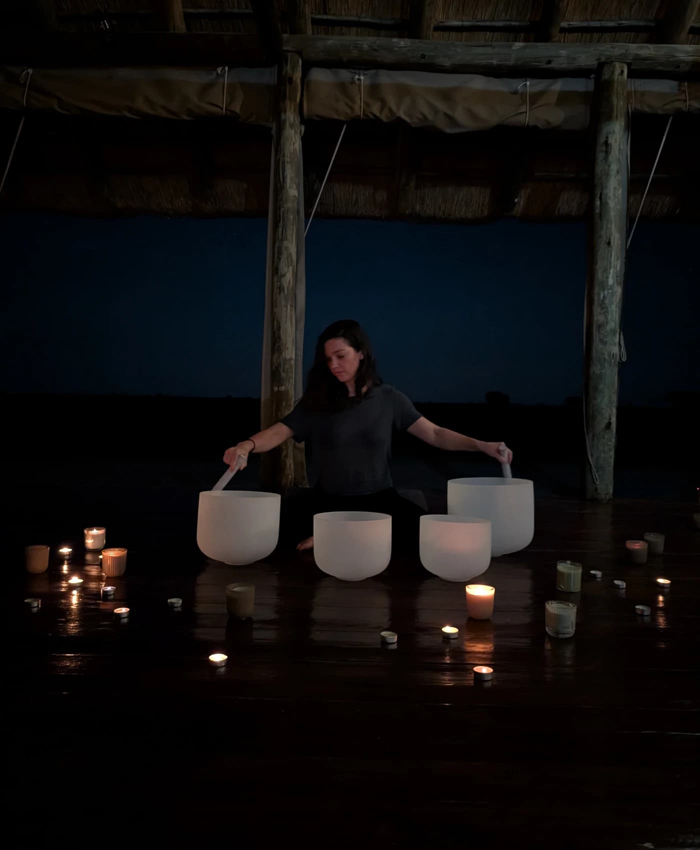 Une séance de bols en cristal à la lueur des bougies dans le shala, après la tombée de la nuit
