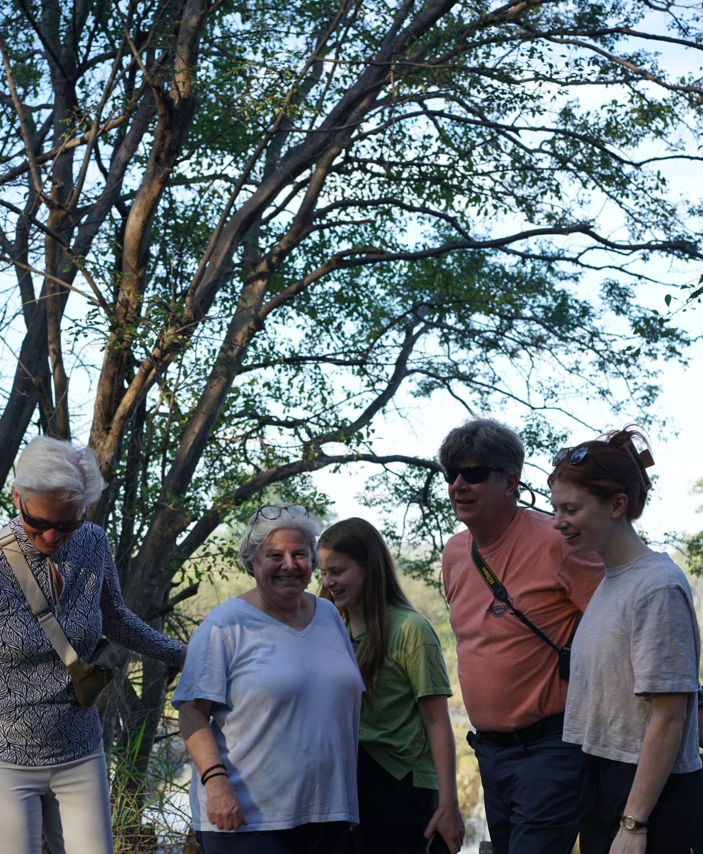 Des voyageurs marchent ensemble et rient sous les arbres lors d’une balade dans la brousse